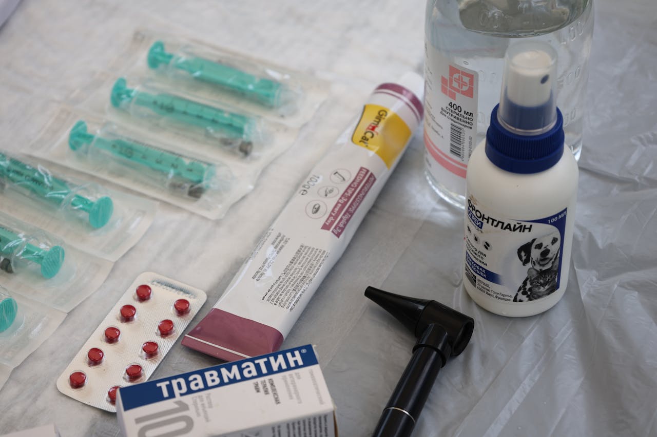 Veterinary medical supplies including syringes, pills, and spray displayed on a table.